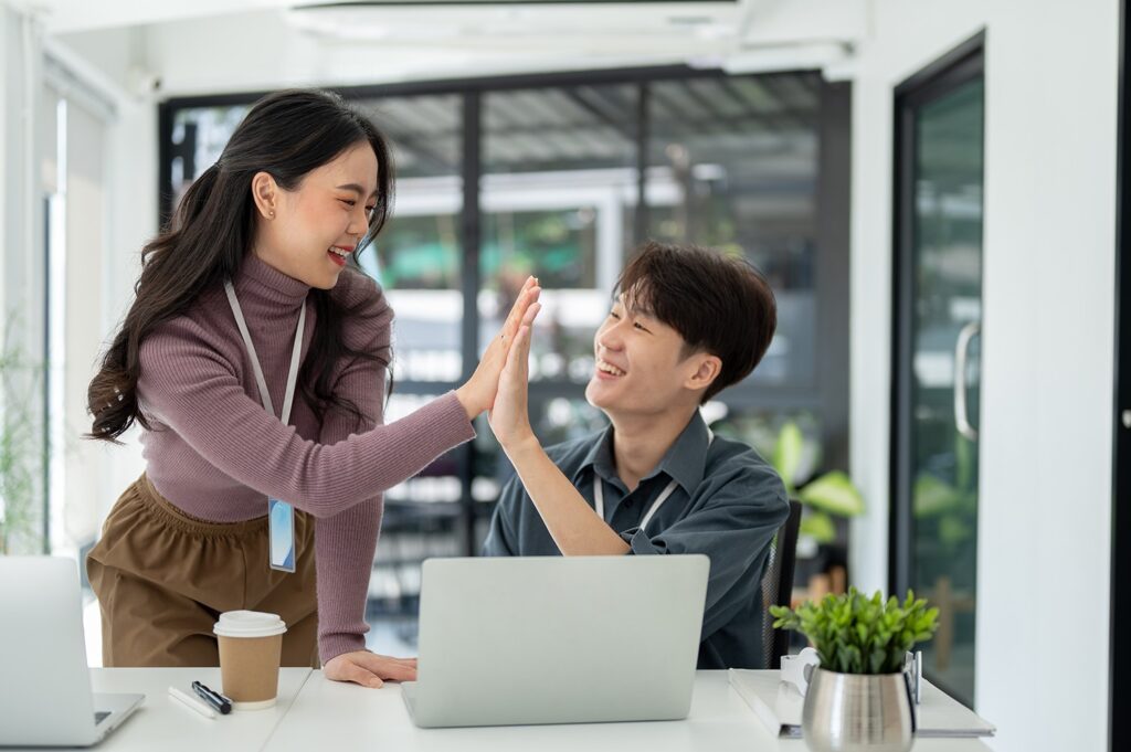 two cheerful business people give high fives each other celebrate their successful project